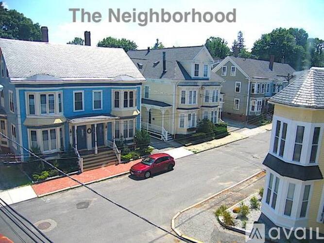 A red car is parked on a street in a residential neighborhood.