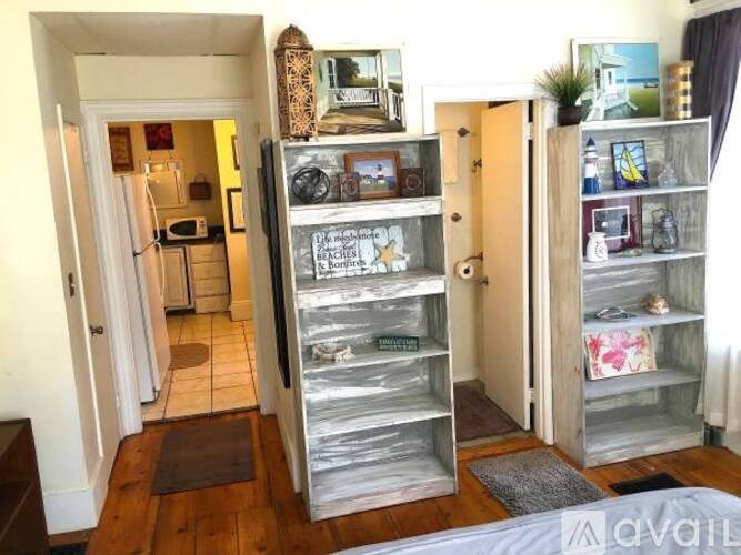 A room with a refrigerator and a shelf with various objects on it.