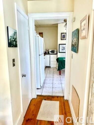 A hallway with a rug on the floor and pictures on the wall.