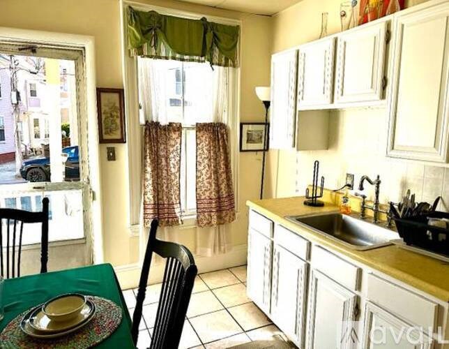 A kitchen with a table and chairs and a window with curtains.