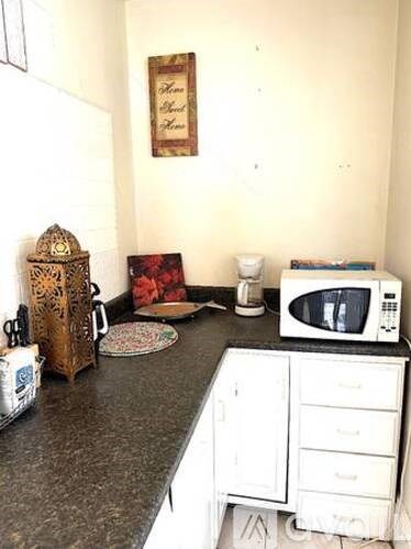 A kitchen with a microwave, a white fridge, and a white cabinet.