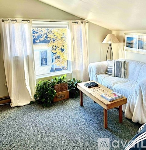 A living room with a couch, a table, and a window with curtains.