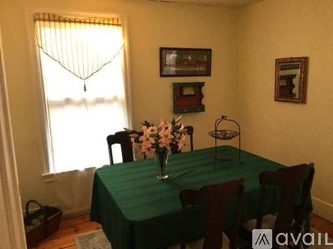 A dining room with a green tablecloth and a vase of flowers on the table.