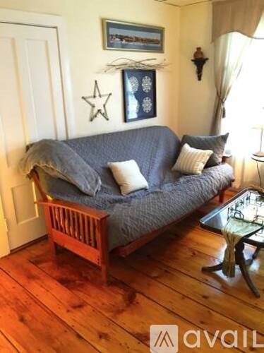 A living room with a grey couch and a wooden chair.