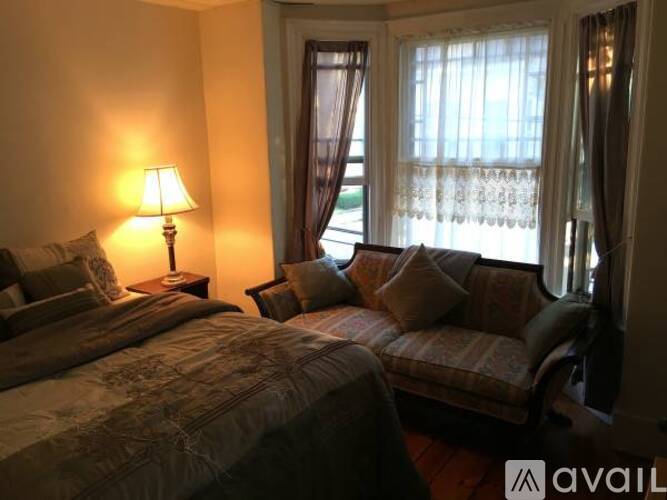 A bedroom with a bed and a couch with a lamp on the side table.