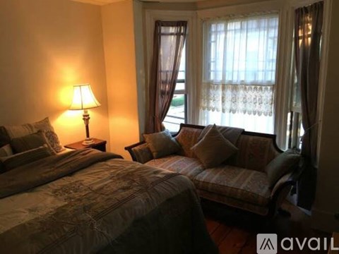 A bedroom with a bed and a couch with a lamp on the side table.