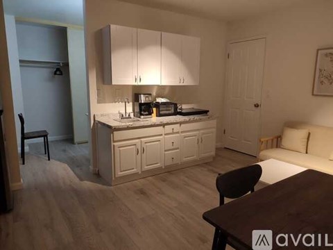 A kitchen with white cabinets and a wooden floor.