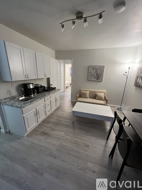 A kitchen with a marble countertop and a white sofa in the background.