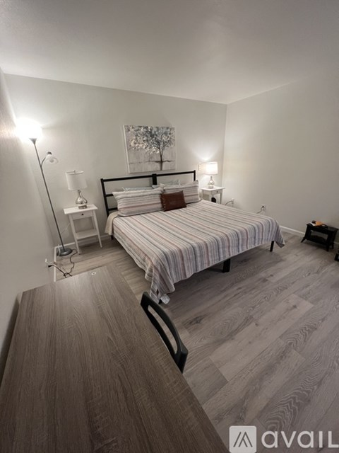 A bedroom with a bed, nightstand, and lamp.