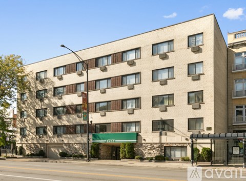 A large beige building with a green awning on the front.