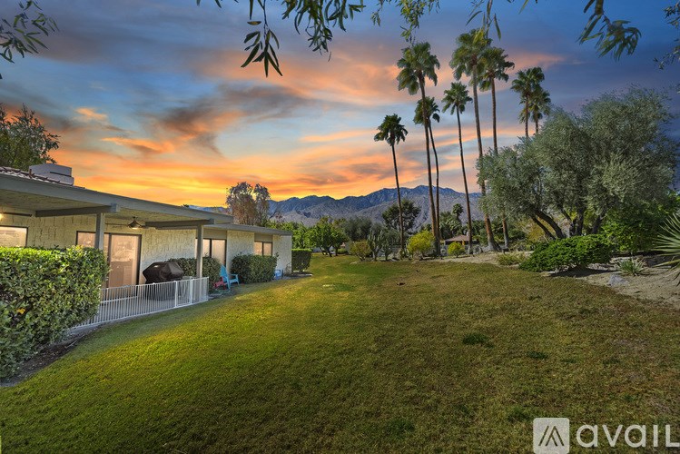 A house with a lawn and palm trees in front of it.