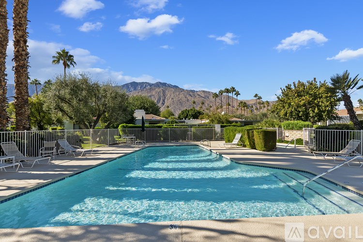 A large swimming pool surrounded by palm trees and mountains.