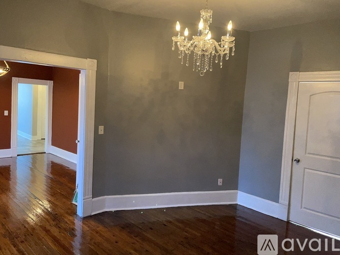 A room with a chandelier and wooden floors.