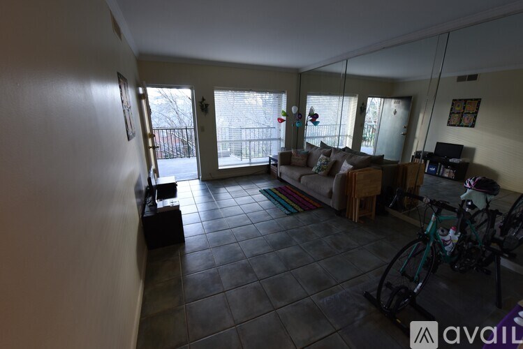 A living room with a couch, a bicycle, and a window.