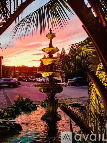 A fountain in the middle of a street with a sunset in the background.