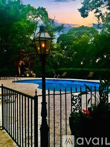 A pool surrounded by a black fence with a lamp post in the foreground.