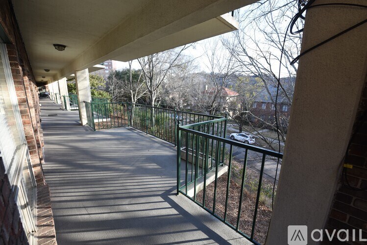 A balcony with a metal railing and a view of a street with cars.