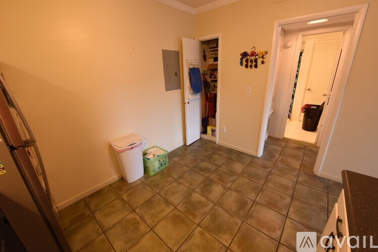 A room with a white door and a white trash can.