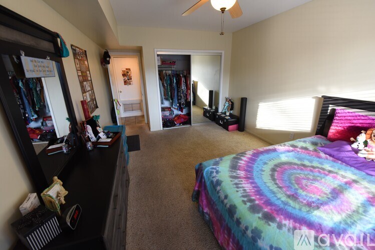 A bedroom with a bed, a wardrobe, and a vanity with a mirror.