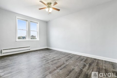 A room with a ceiling fan and a window overlooking a cityscape.