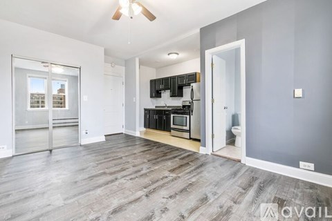 A spacious living room with a kitchen area in the background.