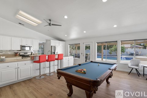 A pool table in a room with a kitchen area.