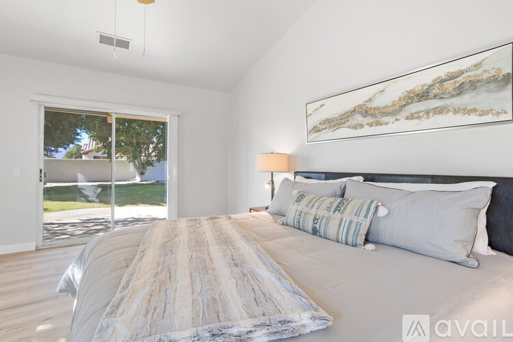 A bedroom with a large bed and a painting on the wall.