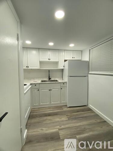 A kitchen with white cabinets and a refrigerator.