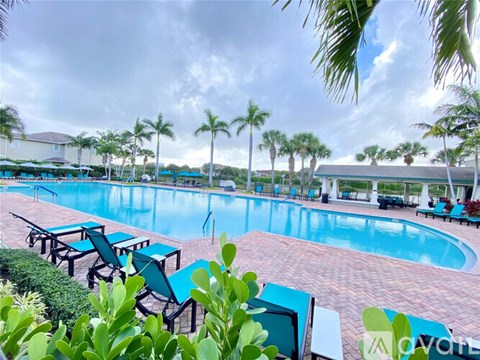 A pool surrounded by palm trees and lounge chairs.