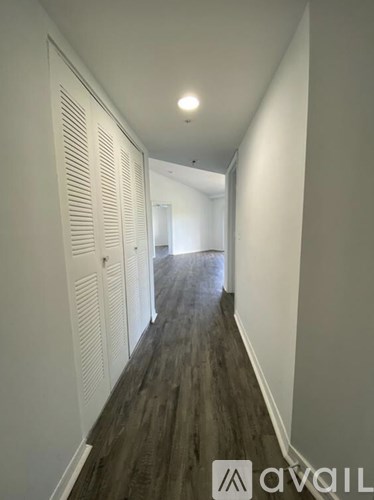 A long hallway with white walls and wood flooring.
