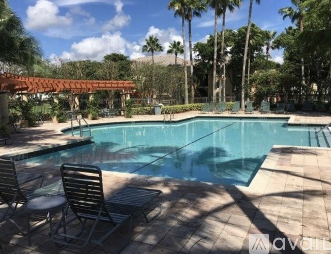 A pool surrounded by palm trees and a shaded area.