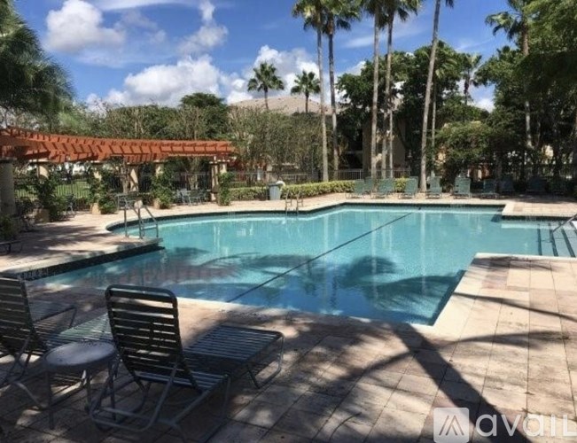 A pool surrounded by palm trees and a shaded area.