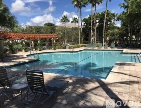 A pool surrounded by palm trees and a shaded area.