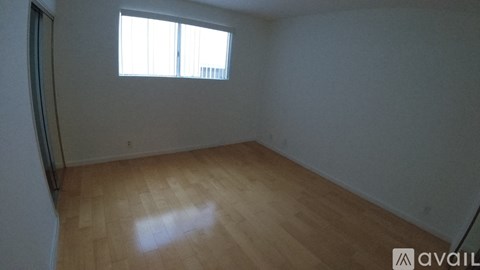 A room with wooden flooring and a window letting in light.
