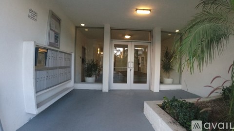 A white building with a glass door and a plant in front.