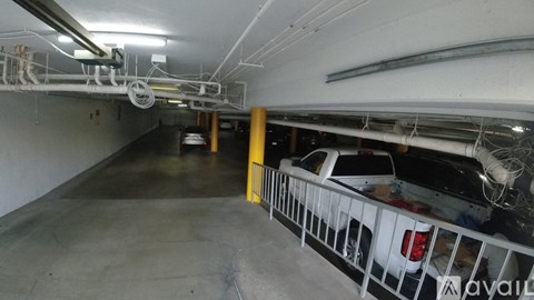 A car is parked in a garage with a yellow pole and a white railing.