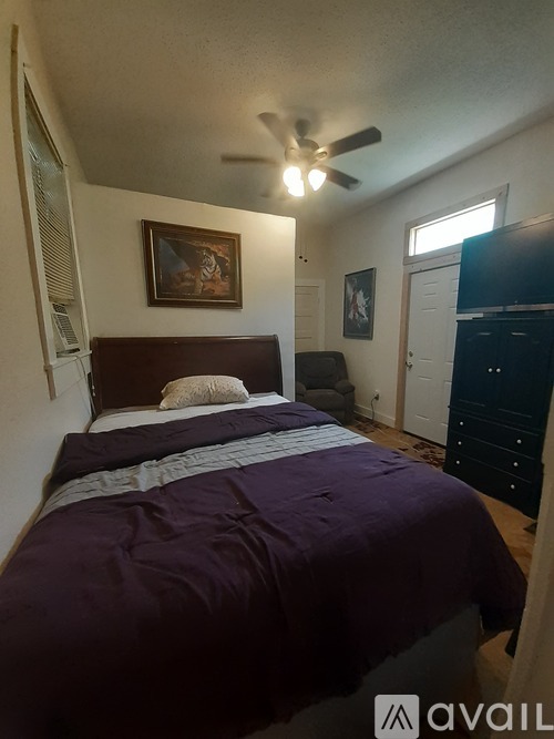 A bedroom with a bed, dresser, and ceiling fan.