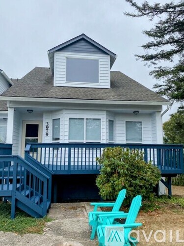A house with a blue front porch and two green chairs in front.