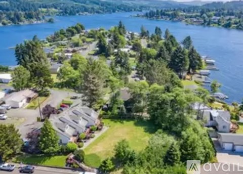 A bird's eye view of a residential area with houses, trees, and a body of water.
