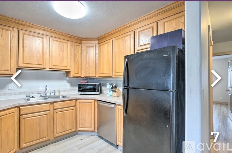 A kitchen with wooden cabinets and a black fridge.