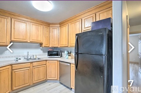 A kitchen with wooden cabinets and a black fridge.