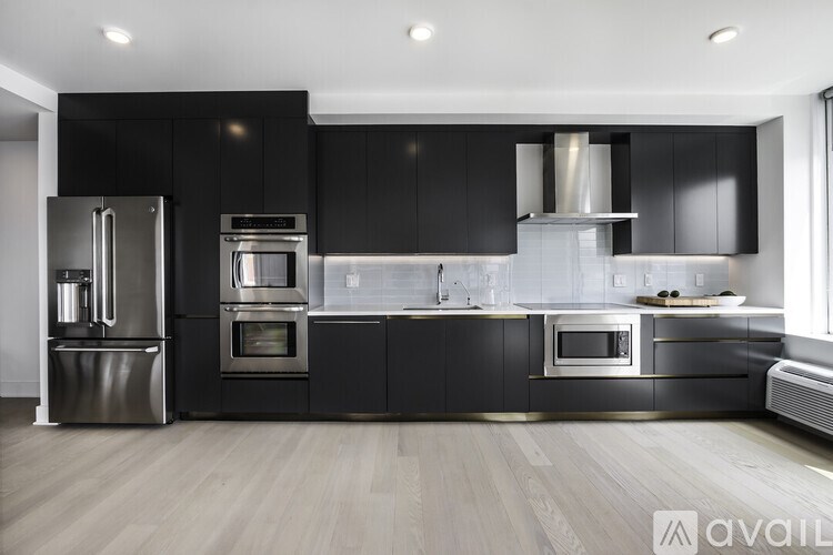 A modern kitchen with black cabinets and stainless steel appliances.