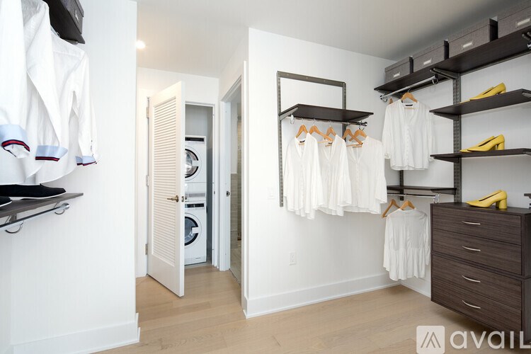 A laundry room with a washer and dryer, a coat rack with several coats hanging, and a wooden chest of drawers.
