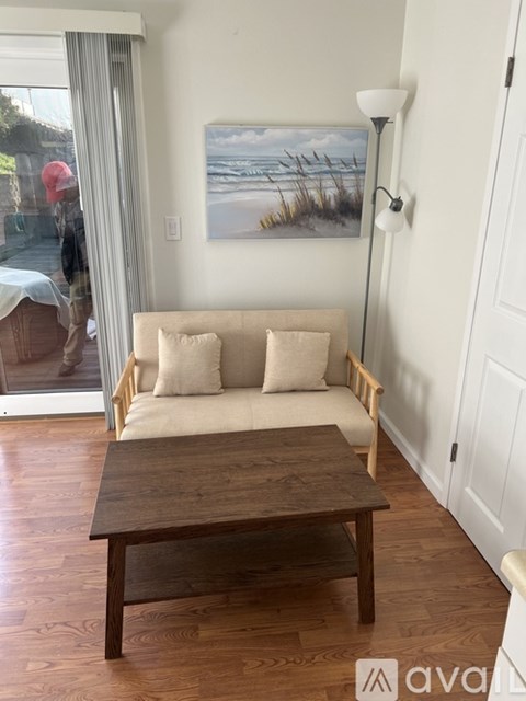 A living room with a couch, a painting of a beach scene, and a wooden coffee table.