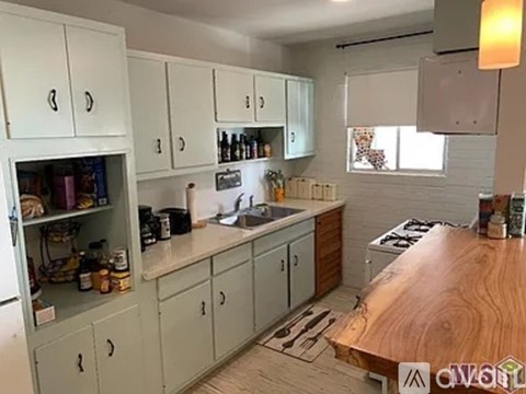 A kitchen with white cabinets and a wooden counter.