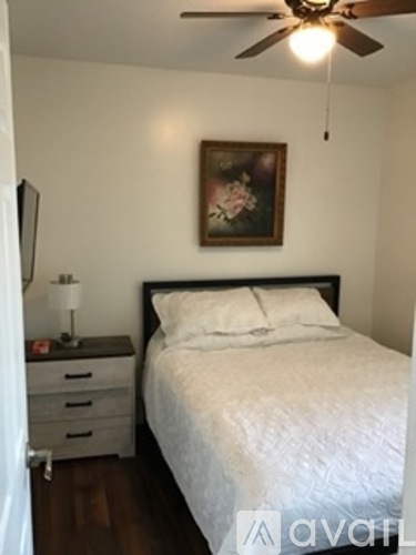 A bedroom with a bed, nightstand, and a painting on the wall.