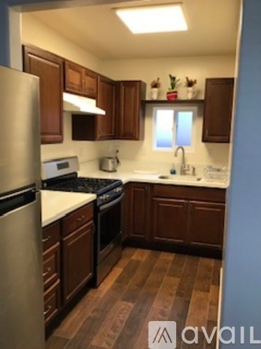 A kitchen with wooden cabinets and a stainless steel refrigerator.
