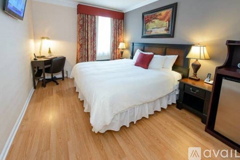A bedroom with a large bed, a desk, and a chair.