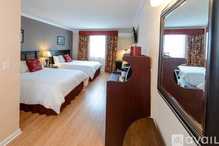 A hotel room with two beds and a wooden headboard.