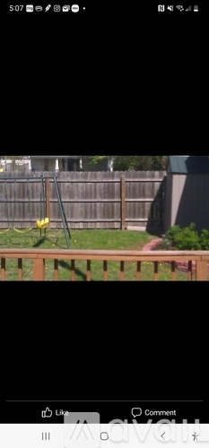 A yellow bird is perched on a wooden fence.